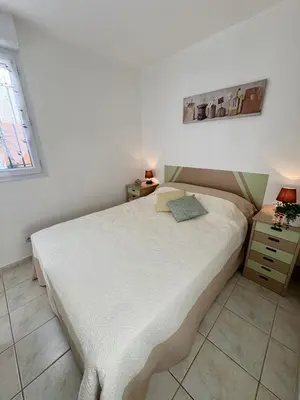 a bedroom with a large white bed and a nightstand at Pavillon avec piscine à deux pas de la plage in Gruissan