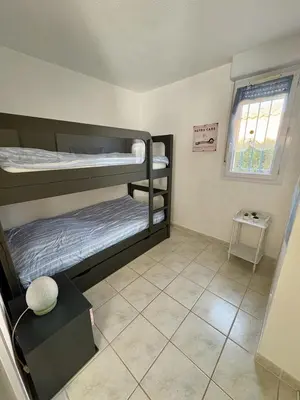 a room with two bunk beds and a window at Pavillon avec piscine à deux pas de la plage in Gruissan