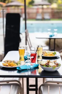 a table with two plates of food and two glasses of beer at Camping La Tour de France in Latour-de-France