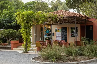 a building with a table and chairs in a garden at Camping La Tour de France in Latour-de-France