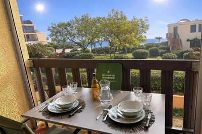 a table with plates and wine glasses on a balcony at Le Petit Grazel in Gruissan