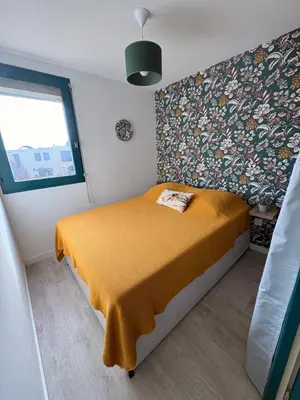 a small bedroom with a bed with a yellow blanket at Le Petit Grazel in Gruissan