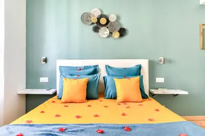 a bedroom with a bed with orange and blue pillows at Le Bourget - Suite et Envolée romantique avec Jacuzzi in Narbonne