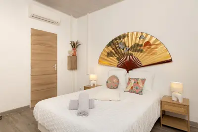 a bedroom with a white bed with a painting on the wall at Kavi-T3 Cozy - Medieval City 4 min - Air-Conditioning-Parking in Carcassonne