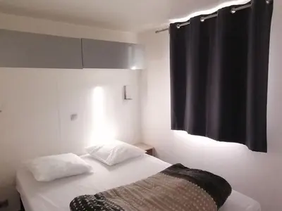 a bedroom with a bed with a black curtain at Mobil-home 2 pers. avec terrasse à Axat - API-1-52-1188 in Axat