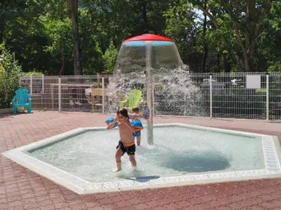 two children playing in a fountain in a pool at Mobil-home 2 pers. avec terrasse à Axat - API-1-52-1188 in Axat