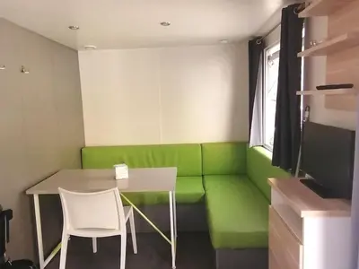 a room with a green couch and a table and chairs at Mobil-home 2 pers. avec terrasse à Axat - API-1-52-1188 in Axat