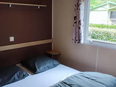 a bedroom with a bed and a window at Mobil home avec Terrasse, 2 Chambres, 5 Personnes - API-1-52-1140 in Axat