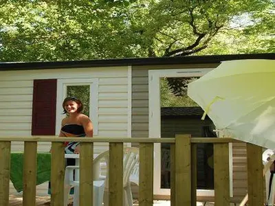 a woman standing on a porch of a house at Mobil home avec Terrasse, 2 Chambres, 5 Personnes - API-1-52-1140 in Axat