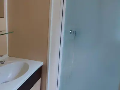 a bathroom with a sink and a glass shower door at Mobil home avec Terrasse, 2 Chambres, 5 Personnes - API-1-52-1140 in Axat