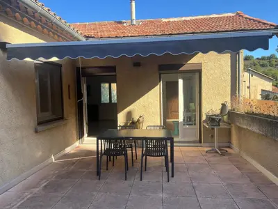 a table and chairs on a patio with a blue awning at MCC House, cozy accommodation with terrace and BBQ in Quillan