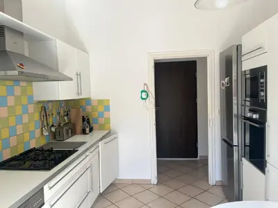 a kitchen with white cabinets and a black refrigerator at MCC House, cozy accommodation with terrace and BBQ in Quillan
