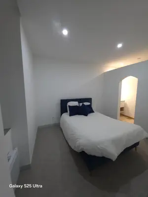 a bedroom with a white bed with blue pillows at YZA Lodge 2026 in Castelnaudary