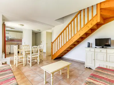 a living room with a staircase and a table and chairs at P Minervois J N07 Villa 3P4 in Homps