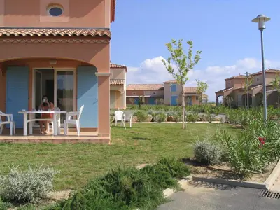 a woman sitting at a table on the porch of a house at P Minervois J N07 Villa 3P4 in Homps