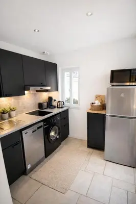 a kitchen with black cabinets and a washer and dryer at Magnifique T3 - à 5 min de la Cité Médiévale in La Celle-sous-Gouzon
