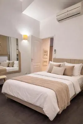 a white bedroom with a large bed and a mirror at Magnifique T2 - à 5 min de la Cité Médiévale in Carcassonne