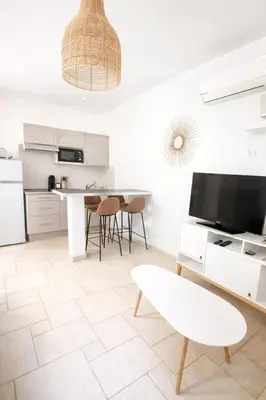 a kitchen with white cabinets and a table and chairs at Charmant T2 - à 5 min de la Cité Médiévale in Carcassonne