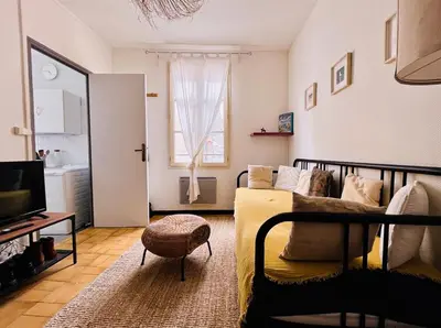 a living room with a bed and a television at Studio à 5 min des halls in Narbonne