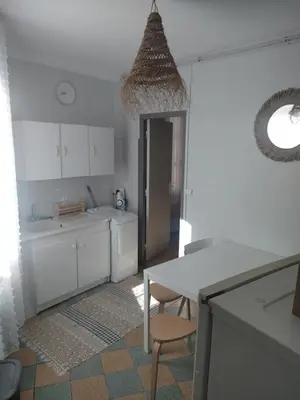 a kitchen with white cabinets and a table and a chair at Studio à 5 min des halls in Narbonne
