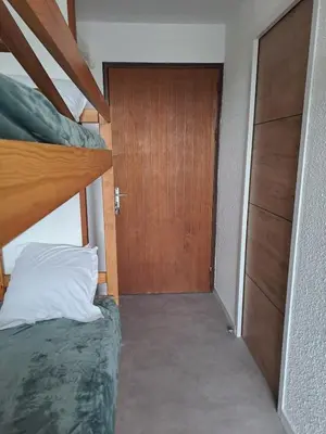a bedroom with two bunk beds and a wooden door at Studio rénové avec piscine et accès direct plage in Gruissan