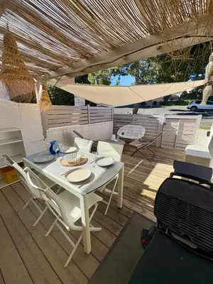 a white table and chairs on a wooden deck at Pavillon rénové avec terrasse & piscine in Gruissan