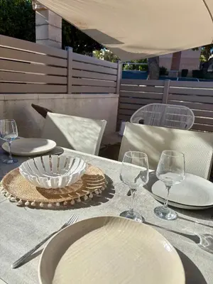 a table with white plates and wine glasses on it at Pavillon rénové avec terrasse & piscine in Gruissan