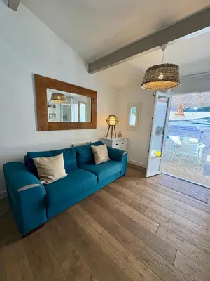 a blue couch in a living room with a window at Pavillon rénové avec terrasse & piscine in Gruissan