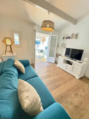 a living room with a blue couch and a television at Pavillon rénové avec terrasse & piscine in Gruissan