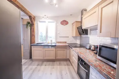 a kitchen with wooden cabinets and a large window at Terrasse et parking a 500m de la Cite AR in Carcassonne