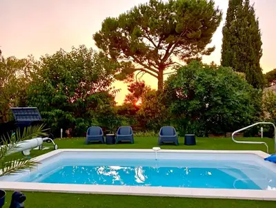 a swimming pool in a yard with chairs and a tree at Villa Pamprenelle in Poilhès