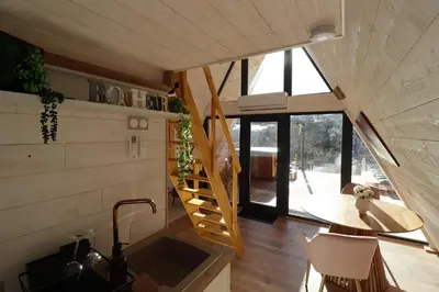 a tiny house with a staircase and a table at L'Amoré - Cabane en A avec spa privatif in Durban-Corbières