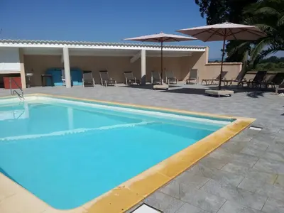 a pool with chairs and umbrellas next to a house at Domaine De L'aube Des Temps in Raissac-dʼAude