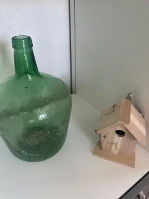 a green glass bottle and a bird house on a counter at Ma petite chaumière in Bouilhonnac