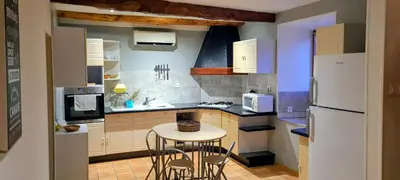 a small kitchen with a table and a refrigerator at Gîte La Bastide Saint-Roc Haute Vallée de l'Aude in Antugnac
