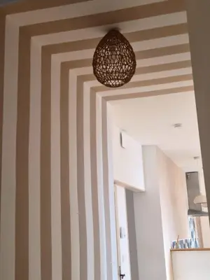 a room with striped walls and a pendant light at Le Damier in Castres