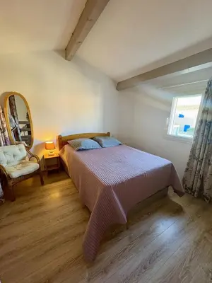 a bedroom with a bed and a chair and a window at Pavillon familial à deux pas de la plage in Gruissan