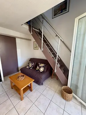 a living room with a couch and a staircase at Pavillon familial à deux pas de la plage in Gruissan
