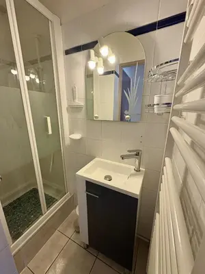 a bathroom with a sink and a shower and a mirror at Pavillon familial à deux pas de la plage in Gruissan