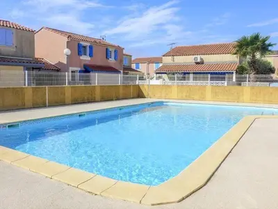 a large swimming pool with blue water in a yard at Pavillon familial à deux pas de la plage in Gruissan