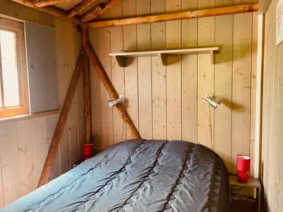 a room with a bed in a room with wooden walls at Cabane sur pilotis avec terrasse au calme - API-1-52-1502 in Camon