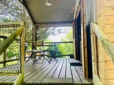 a porch of a cabin with a table and chairs at Cabane sur pilotis avec terrasse au calme - API-1-52-1502 in Camon