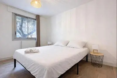 a bedroom with a large white bed with a window at Le Carnot - Spacieux appartement pour 8 personnes - Proche Gare in Narbonne
