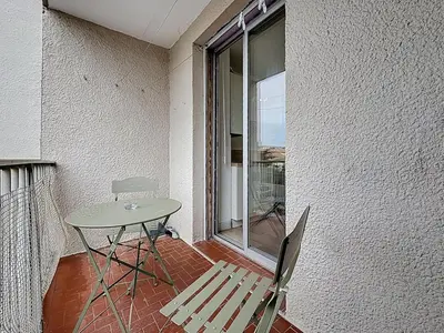 a table and a chair on a balcony with a window at Le Carnot - Spacieux appartement pour 8 personnes - Proche Gare in Narbonne