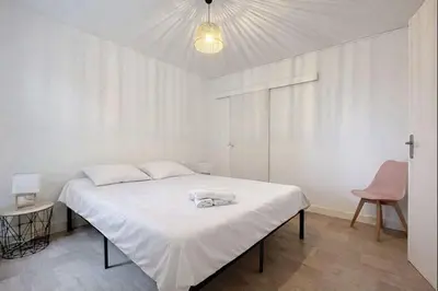 a white bedroom with a bed with towels on it at Le Carnot - Spacieux appartement pour 8 personnes - Proche Gare in Narbonne