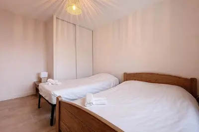two beds in a small room with white sheets at Le Carnot - Spacieux appartement pour 8 personnes - Proche Gare in Narbonne