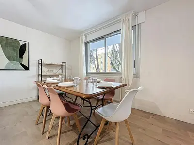 a dining room with a table and chairs and a window at Le Carnot - Spacieux appartement pour 8 personnes - Proche Gare in Narbonne
