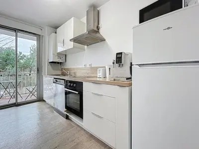 a kitchen with white cabinets and a refrigerator at Le Carnot - Spacieux appartement pour 8 personnes - Proche Gare in Narbonne