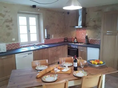 a kitchen with a wooden table with a bottle of wine at Holiday Home Gemütliches Ferienhaus in Villautou by Interhome in Villautou