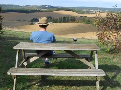 a person sitting on a picnic table with a glass of wine at Holiday Home Haus für 6 Personen und 8 Kinder in Villautou by Interhome in Villautou